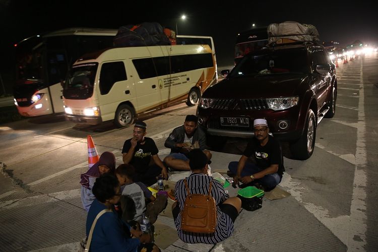 Alam, pemudik asal Kebon jeruk, Jakarta Barat, menggelar tikar untuk menyantap makan malam yang diabwanya dari rumah. Alam beristirahat di KM 86 A jalan Tol Cikopo-Palimanan (Cipali) pada Sabtu (1/6/2019).