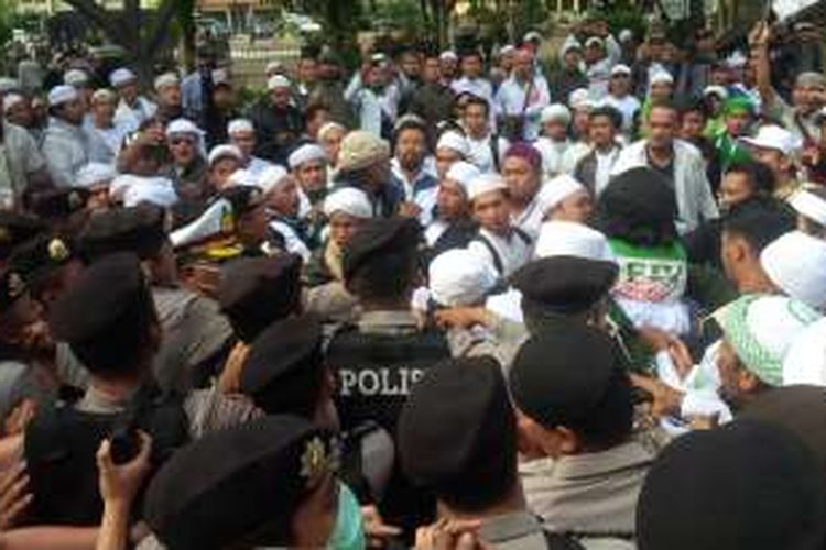 Anggota Polisi dan pendukung Rizieq Shihab yang mencoba masuk ke Markas Polda Jawa Barat sempat terlibat aksi saling dorong. Kondisi sedikit memanas karena mereka menolak didorong mundur. KOMPAS.com/Putra Prima Perdana.