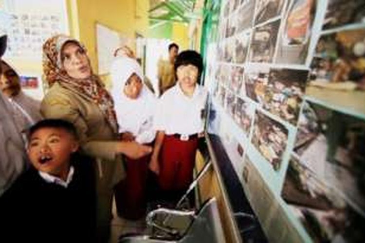 Sejumlah siswa SLB B Negeri, Kabupaten Garut, Jawa Barat, belajar mengenai bencana banjir bandang melalui foto-foto dokumentasi kondisi sekolah mereka saat terkena banjir bandang, Senin (26/9). Meski masih dalam suasana tanggap darurat bencana, sejumlah sekolah yang terkena bencana banjir bandang mulai melakukan kegiatan belajar-mengajar.