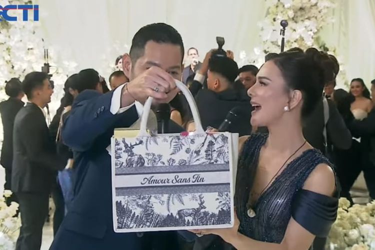 Pembawa acara Evan Sanders (kiri) dan Astrid Tiar (kanan) memperlihatkan tas souvenir pernikahan Amanda Manopo dan Kenny Agustin di The Langham, Jakarta Selatan, Jumat (10/10/2025).