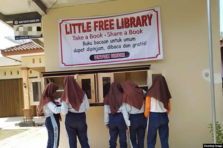 Lima siswi melihat-lihat buku di Little Free Library yang dipasang di teras rumah seorang guru di desa Rawajaya, Kabupaten Cilacap.