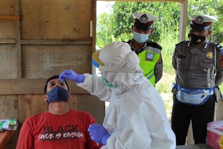 Petugas saat mengambil sampel rapid tes antigen para pengendara yang tidak dapat menunjukkan surat antigen yang masih berlaku di perbatasan Jambi-Sumatera Selatan