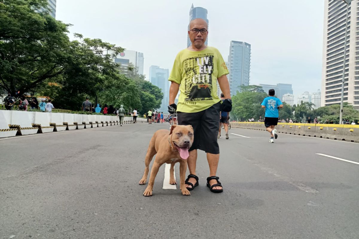 Ketua Forum Warga Kota Jakarta (Fakta) Azas Tigor Nainggolan bersama Alpen, anjing kesayangannya, saat berfoto di area car free day, Minggu (10/10/2022).