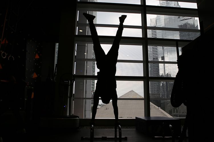 Seorang instruktur memeragakan gerakan handstand di pusat kebugaran 
