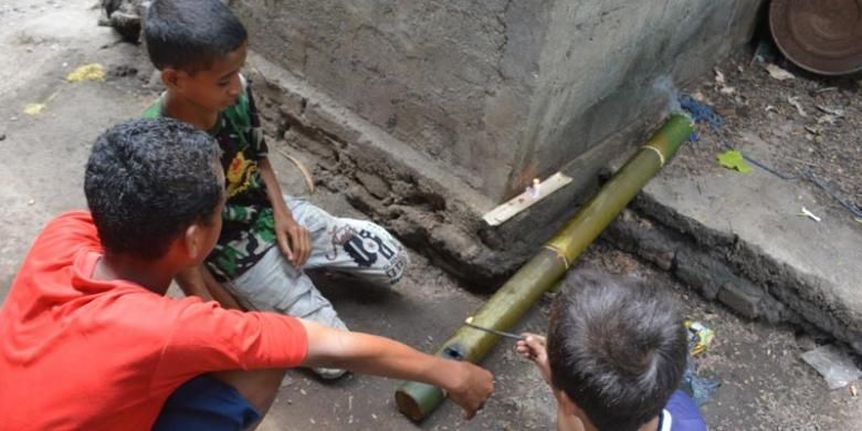 Tiga orang anak sekolah dasar di Kompleks Mabako, Kelurahan Watunggene, Kecamatan Kota Komba, Manggarai Timur, Flores, NTT, Jumat (19/12/2014) membunyikan meriam bambu di samping rumah mereka. Tradisi meriam bambu merupakan warisan leluhur orang Flores untuk menyambut kelahiran Isa Almasih.  