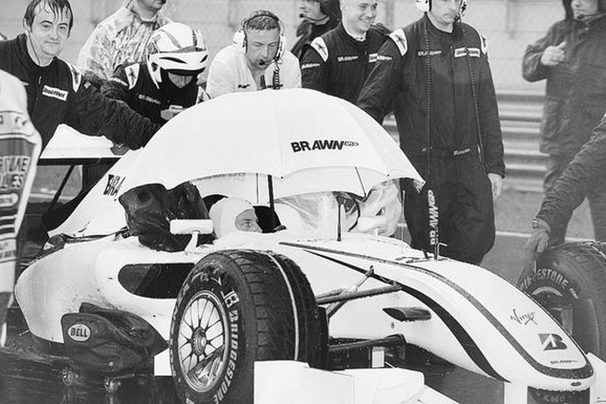 Pebalap Brawn GP, Jenson Button (Inggris), berteduh di bawah payung saat hujan dalam balapan F1 di Sepang, Kuala Lumpur, Malaysia, Minggu (5/4). Jenson Button mengungguli pebalap BMW Sauber, Nick Heidfeld (Jerman), dan pebalap Toyota, Timo Glock (Italia), dalam balapan yang dihentikan setelah 32 lap dari seharusnya 56 lap karena hujan.