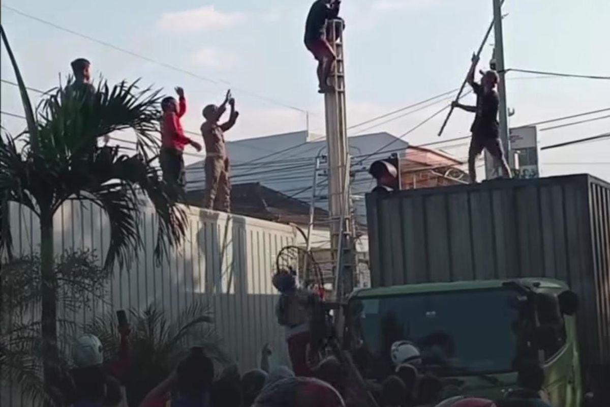 Foto: Seorang pria depresi naik ke tiang penerangan jalan umum (PJU) sambil berteriak histeris pada Minggu (20/7/2025). 