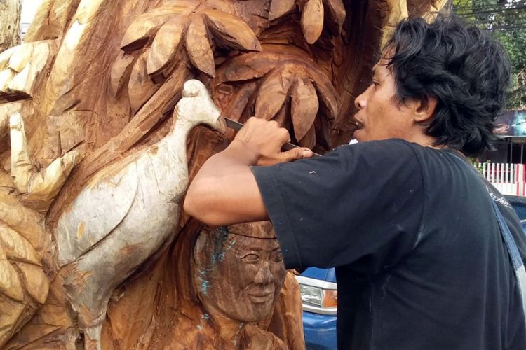 Seniman pahat Gorontalo, Pipin Idris sedang membentuk burung Maleo (Macrocephalon maleo) pada sebuah pohon mati di RTH taman Kota.