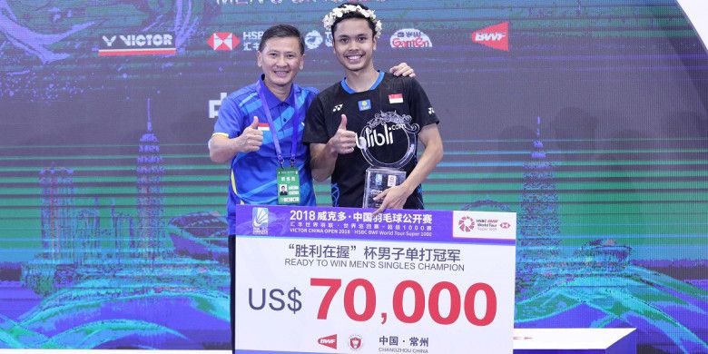 Pebulu tangkis tunggal putra Indonesia, Anthony Sinisuka Ginting, berpose di atas podium juara bersama sang pelatih, Hendry Saputra, setelah mengalahkan Kento Momota (Jepang) pada laga final turnamen China Open 2018 di Changzhou, Minggu (23/9/2018).
