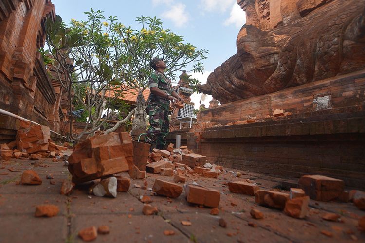 Prajurit TNI memantau kerusakan pada bagian candi yang runtuh akibat gempa di Pura Lokanatha, Denpasar, Bali, Selasa (16/7/2019). Gempa yang mengguncang Bali pada magnitudo 6 (selanjutnya dilakukan pemutakhiran menjadi magnitudo 5,8) pukul 08.18 Wita tersebut tidak menimbulkan korban jiwa, tapi sejumlah bangunan di beberapa kawasan di Bali mengalami kerusakan.