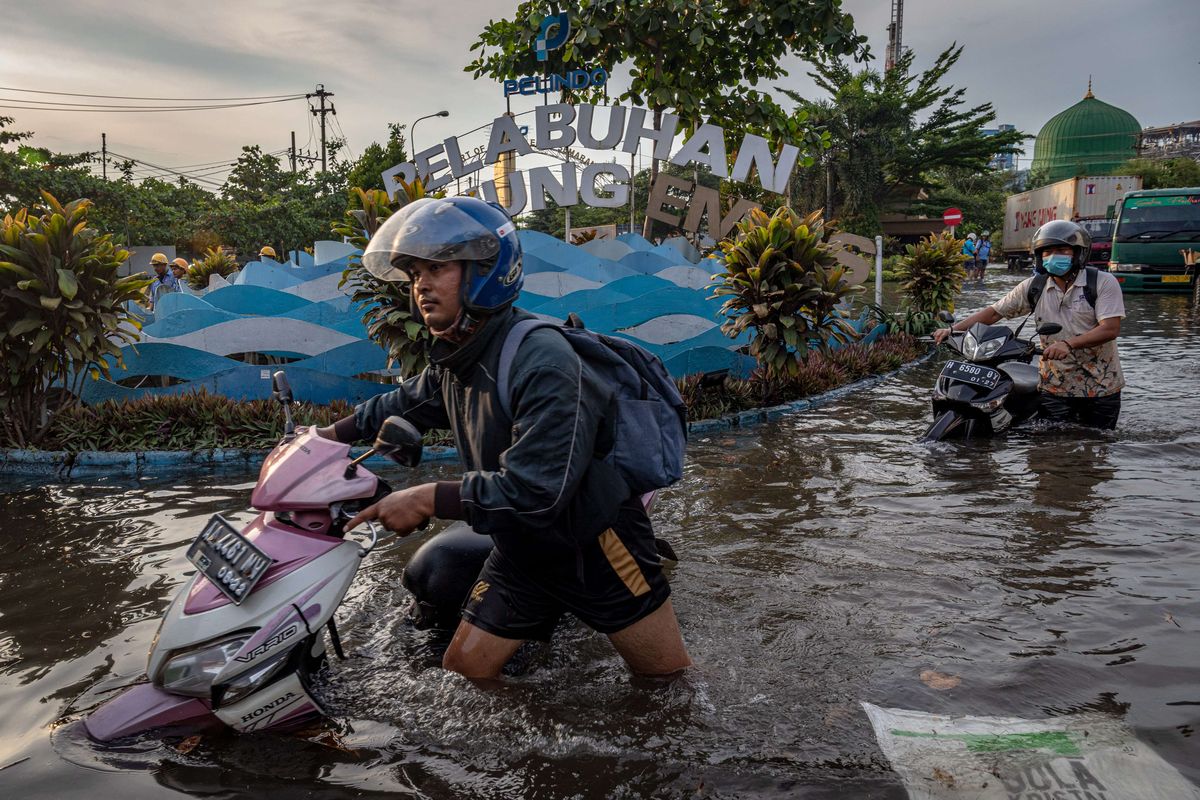 Sejumlah pekerja mendorong motornya yang mogok untuk menerobos banjir rob atau limpasan air laut ke daratan yang merendam kawasan Pelabuhan Tanjung Emas Semarang, Jawa Tengah, Senin (23/5/2022). Banjir rob dengan ketinggian bervariasi hingga mencapai 1,5 meter itu disebabkan oleh tingginya pasang air laut serta adanya tanggul yang jebol di kawasan tersebut. Sementara itu personel dari Basarnas, TNI-Polri dan relawan diterjunkan untuk membantu evakuasi para pekerja maupun warga.