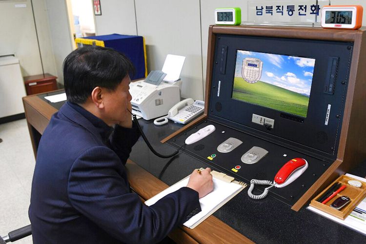 Dalam file foto 3 Januari 2018 yang dirilis oleh Kementerian Unifikasi Korea Selatan, seorang pejabat pemerintah Korea Selatan berkomunikasi dengan seorang perwira Korea Utara selama panggilan telepon di hotline komunikasi khusus di desa perbatasan Panmunjom di Paju, Korea Selatan .