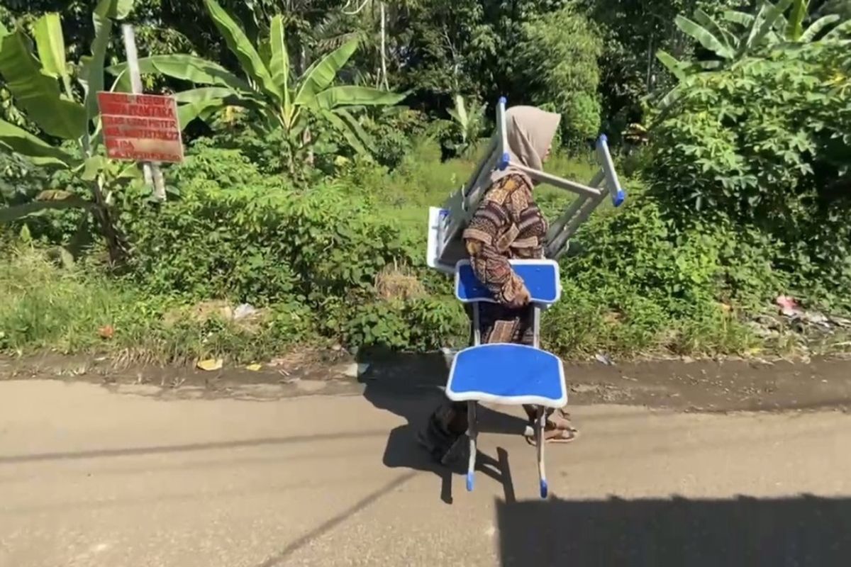 Arta Grace Monica (35) orang tua murid di Kabupaten Lebak menggotong meja dan kursi seorang diri ke sekolah setelah anaknya dituduh merusak, Senin (28/4/2025)