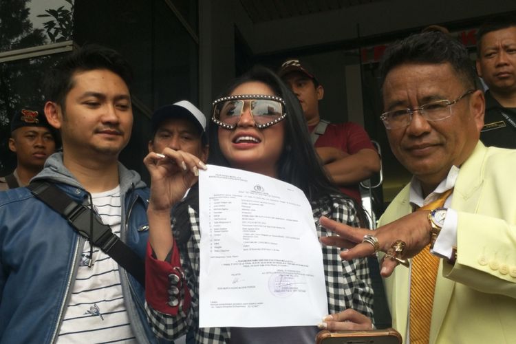 Dewi Perssik didampingi suaminya Angga Wijaya (kiri) dan kuasa hukumnya, Hotman Paris (kanan), saat melaporkam keponakannya Rosa Meldianti ke Polda Metro Jaya, Jakarta Selatan, Senin (5/11/2018).