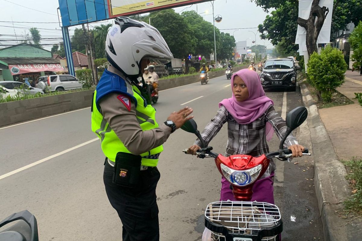 Anggota polisi menegur seorang pengendara sepeda listrik yang masuk jalan umum