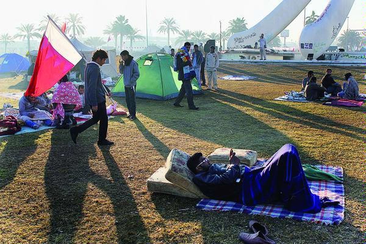 Seorang pengunjuk rasa antipemerintah mengirim pesan singkat dari telepon genggamnya saat pagi tiba setelah bersama pengunjuk rasa lain berkemah di bundaran Pearl di pusat kota Manama, Bahrain, Minggu (20/2). Demonstran kembali menduduki tanah lapang itu setelah tentara dan polisi menarik diri, sehari sebelumnya.