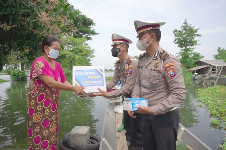 AKP Aristianto Budi Sutrisno bersama jajaran Satlantas Polres Lamongan saat menyerahkan bantuan sembako dan membagikan masker bagi warga terdampak banjir Bengawan Njero di Lamongan.