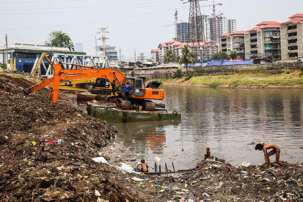 Sejumlah anak-anak mencari sampah berupa besi saat pekerja mengeruk lumpur menggunakan ekskavator di Kanal Banjir Barat (KBB) sungai Ciliwung di Tanah Abang, Jakarta Pusat, Senin (11/9/2017). Pengerukan lumpur dilakukan untuk memperlancar aliran air sungai serta mengantisipasi datangnya musim hujan yang mengakibatkan banjir yang kerap terjadi di Jakarta.