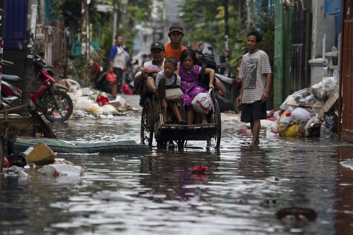 Sejumlah warga melintasi jalan yang tergenang banjir di wilayah Teluk Gong, Penjaringan, Jakarta Utara, Sabtu (4/1/2020).Hujan lebat di awal tahun membuat kawasan teluk gong masih terendam banjir.