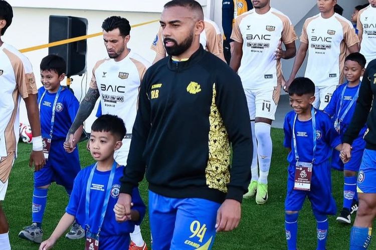 Pemain Arema FC Dalberto Belo menggandeng player escort dari Dendi Santoso Soccer School (DSSS) jelang kick off pekan ke-5 Super league 2025-2026 melawan Dewa united yang berakhir dengan skor 1-2 di Stadion Kanjuruhan Kepanjen, Kabupaten Malang, Sabtu 913/9/2025) sore.