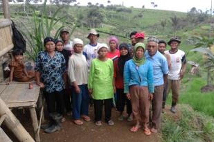 Para petani berfoto di depan saung yang mereka buat sebagai tempat rapat dilatari oleh perkebunan teh dan sawah