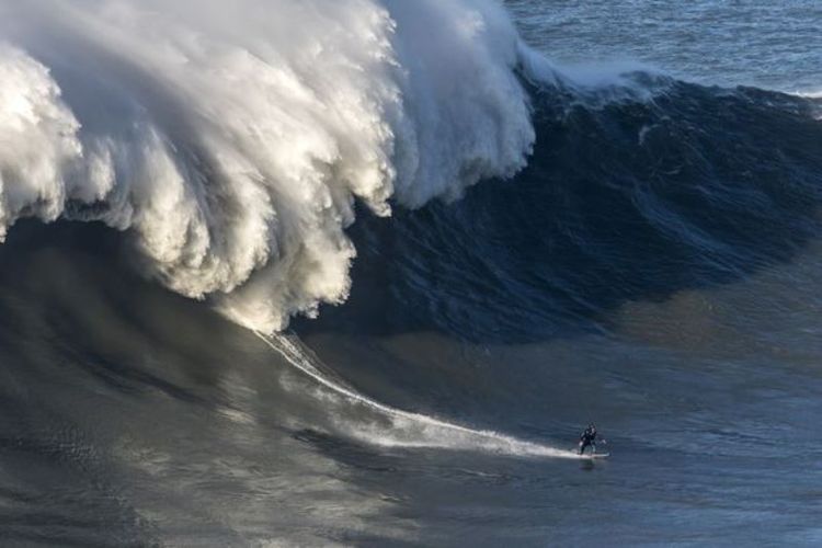 Seorang peselancar Inggris, Andrew Cotton, terekam kamera saat terguyur ombak monster di Nazare, Portugal, Rabu (9/11/2017) waktu setempat. (Daily Mirror)