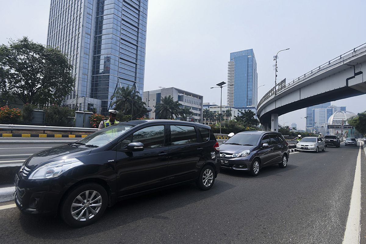 Petugas Ditlantas Polda Metro Jaya memberhentikan sejumlah mobil berpelat nomor genap yang memasuki Jalan Gatot Soebroto, Jakarta, Rabu (1/8/2018). Petugas kepolisian mulai memberlakukan penindakan berupa tilang terhadap pengendara mobil yang melanggar di kawasan perluasan sistem ganjil-genap.