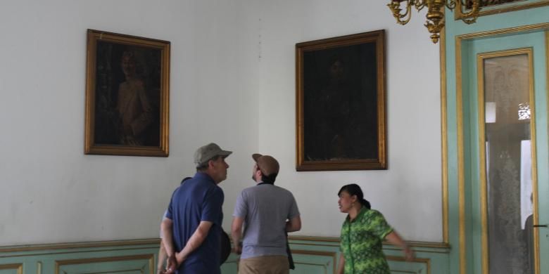 Dua wisatawan mancanegara sedang melihat lukisan yang ada di dalam Pura Mangkunegaran di Solo, Jawa Tengah. Mereka juga mendapat penjelasan dari pemandu wisata.