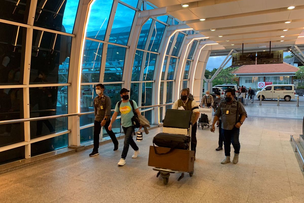 AA, Warga Negara Asing (WNA) yang memiliki dwi kewarganegaraan Rusia dan Jerman (baju kaos biru) dikawal petugas Rudenim Denpasar saat dideportasi melalui Bandara Internasional I Gusti Ngurah Rai Bali pada Selasa (9/8/2022). / Dok. Humas Kemenkumham Bali