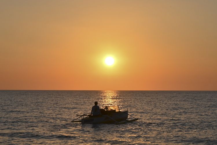 Nelayan Filipina berlayar saat matahari terbenam di pantai Bacnotan, provinsi La Union, wilayah Filipina yang menghadap ke Laut China Selatan.