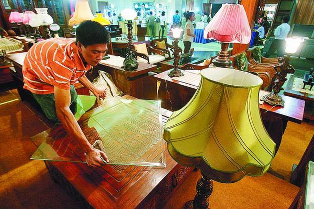 Pekerja memasang kaca pada meja dari kayu jati di salah satu stan produsen mebel lokal pada pameran mebel.