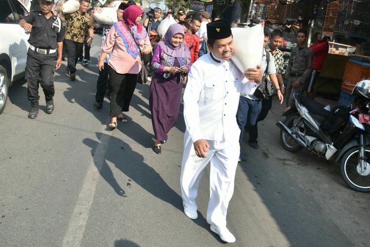 Bupati Purwakarta Dedi Mulyadi memanggul beras untuk dibagikan pada warga miskin di Purwakarta, Kamis (7/9/2017). Kegiatan membagikan beras pada masyarakat miskin merupakan perwujudan dari program Kemis Poe Welas Asih.