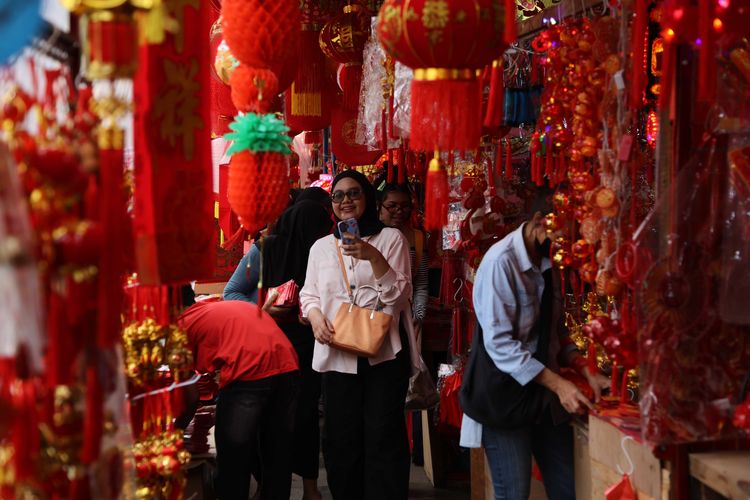 Pengunjung melintas di depan lapak penjual pernak-pernik Imlek di kawasan Pecinan Glodok, Jakarta Barat, Minggu (15/2/2026). Tiap tahun menjelang Imlek kawasan Pecinan Glodok selalu dipadati pengunjung karena menjadi titik pusat jual beli pernak-pernik Imlek.