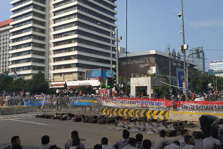 Situasi di depan Bawaslu pada Selasa (21/5/2019). Polisi tampak beristirahat, sedangkan massa aksi yang mengatasnamakan diri sebagai Gerakan Nasional Kedaulatan Rakyat menunaikan salat asar berjamaah. Keduanya dipisahkan pagar berduri.