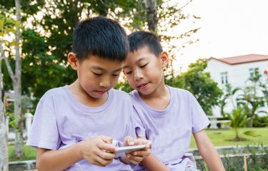 Ilustrasi anak bermain ponsel, gen alpha. Arti bahasa gaul gen alpha, sigma, skibidi, rizz.