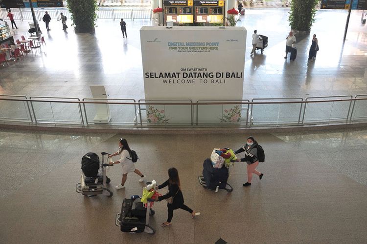 Penumpang pesawat membawa barang bawaannya di Terminal Kedatangan Internasional Bandara Internasional I Gusti Ngurah Rai Bali, Jumat (20/3/2020). Sebanyak 181.053 orang penumpang rute internasional tercatat tiba di bandara tersebut pada periode 1-19 Maret 2020, atau mengalami penurunan 40,2 persen jika dibandingkan catatan periode yang sama pada tahun 2019 yaitu sebesar 302.914 orang penumpang.