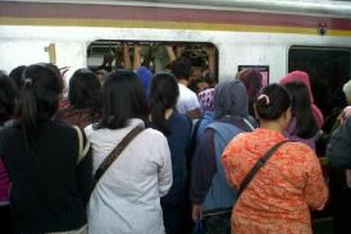 Penumpang di Stasiun Depok berebutan masuk ke KRL, Senin (3/2/2014). Saking padatnya, pintu KRL tidak bisa tertutup.