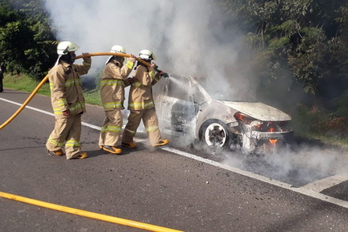 Petugas pemadam kebakaran memadamkan api yang membakar mobil sedan di KM3 Halim Tol Jakarta-Cikampek, Rabu (27/5/2020) pagi. 