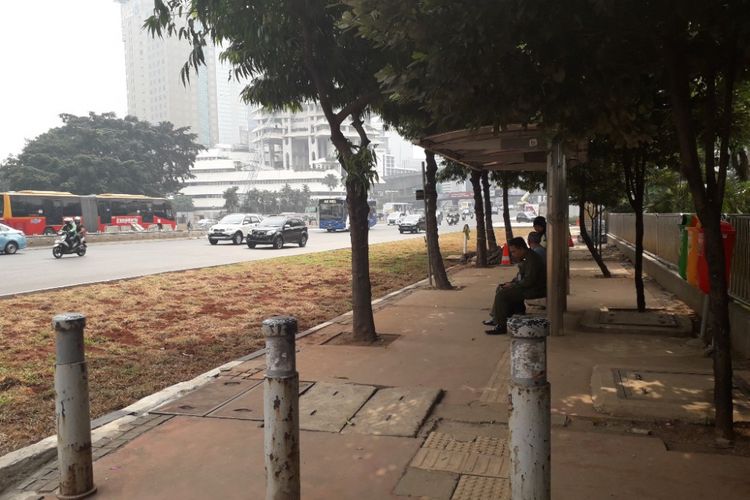 Halte bus di depan Gedung Plaza Sentral, Jalan Jenderal Sudirman, yang terhalang area rerumputan, Selasa (24/7/2018).