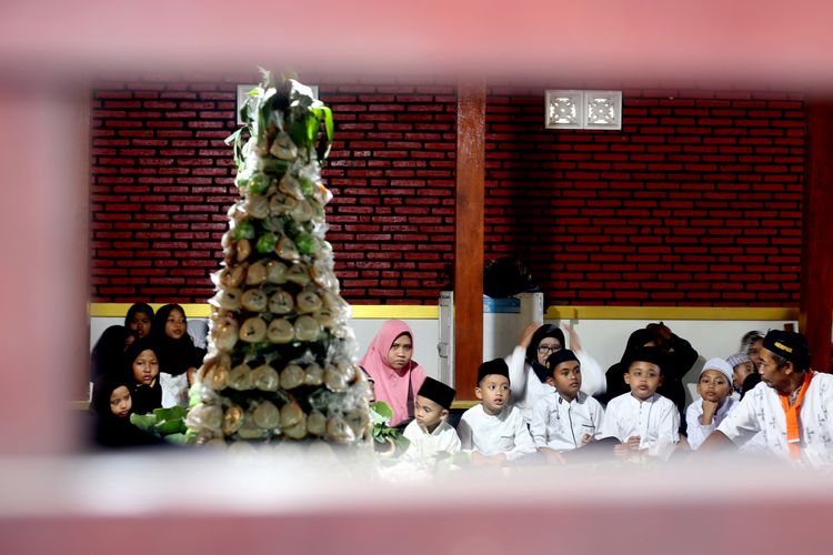 Anak-anak beserta warga duduk dan berdoa secara khidmat melingkari gunungan apem setelah di kirab menuju Pesarean Ki Ageng Gribig Kota Malang, Kamis (27/2/2025) siang.