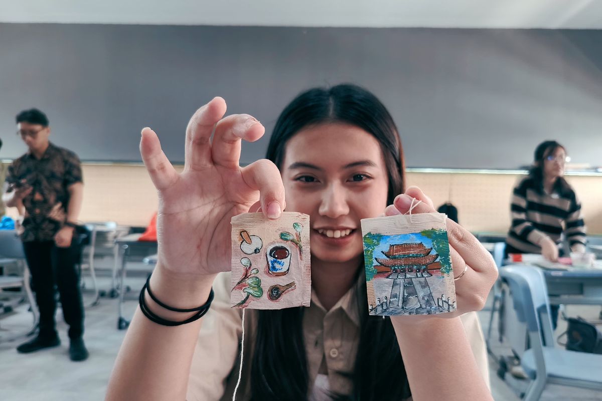 Liona, salah satu Mahasiswa Ubaya menunjukkan hasil karya lukisnya yang menggunakan media kantong teh bekas untuk memperingati hari teh sedunia yang jatuh setiap tanggal 21 Mei.