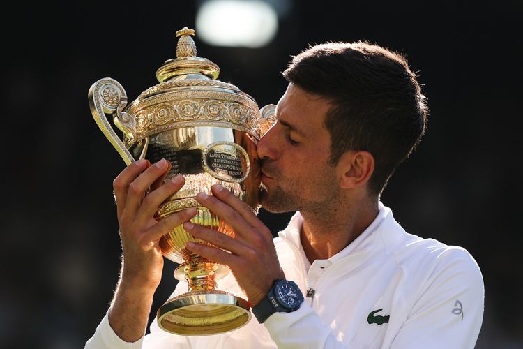 Petenis Serbia, Novak Djokovic, mencium trofi Wimbledon 2022 setelah mengalahkan pemain Australia, Nick Kyrgios, dalam pertandingan final di The All England Tennis Club, Wimbledon, London, Minggu (10/7/2022).