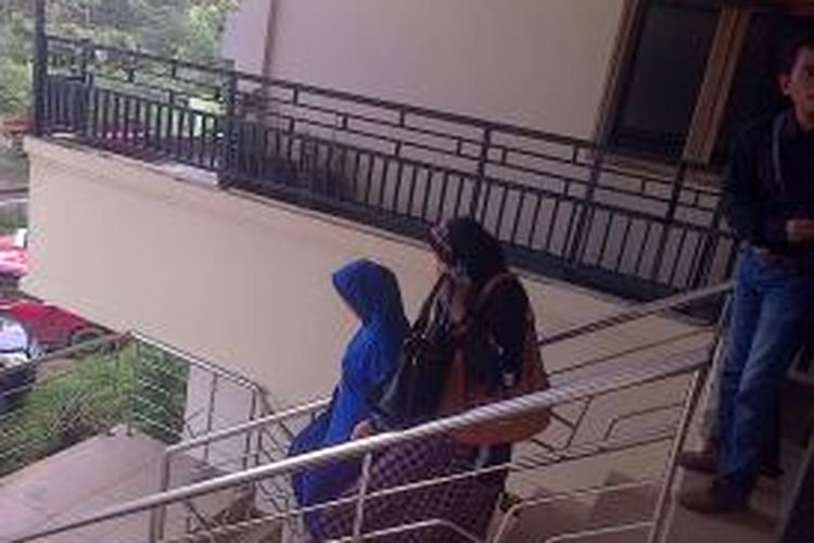 Waode Farida, istri bupati Muna berjilbab biru didampingi kerabatnya menuruni tangga Direktorat Reserse dan kriminal khusus polda Sultra usai diperiksa sebagai saksi dalam kasus dugaan suap CPNSD di Kabupaten Muna.