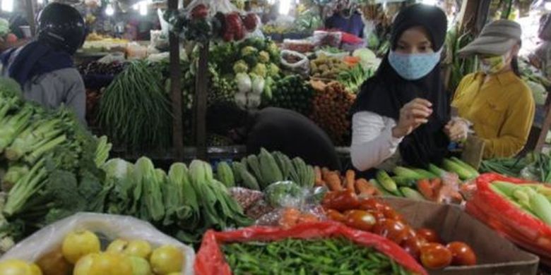 Warga dengan masker memilih sayuran di pasar tradisional Pondok Labu, Jakarta, Minggu (07/06). 