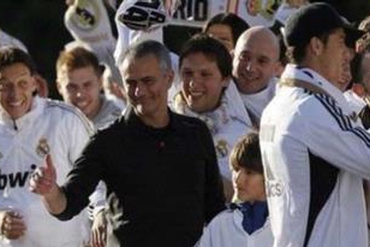 Pelatih Real Madrid, Jose Mourinho (tengah), Cristiano Ronaldo (kanan), dan Mesut Ozil (kiri) berpesta di kawasan Cibeles setelah tim memenangi laga La Liga di Madrid, Kami (3/5/2012). Madrid menang 3-0 atas Athletic Bilbao dan meski menyisakan satu laga sisa, mereka memastikan akan meraih gelar liga sejak tahun, menggulingkan juara bertahan Barcelona. Mourinho menjadi pelatih pertama di Eropa yang berhasil memenangi gelar di empat liga primer di empat negara berbeda.
