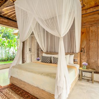 Ilustrasi tempat tidur dengan kelambu tulle untuk menghadirkan nuansa kayaknya villa di Bali. 