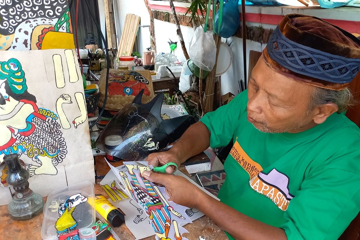 Iskandar saat memotong mengecat Wayang Uwuh yang terbuat dari Plastik, Jumat (13/1/2023)