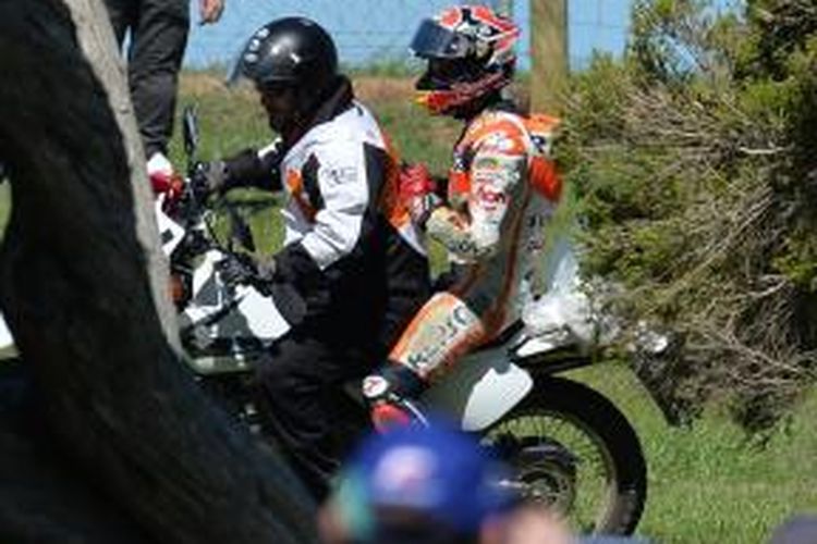 Pebalap Honda asal Spanyol, Marc Marquez, membonceng petugas lintasan untuk kembali ke pit, setelah mengalami kecelakaan pada sesi latihan bebas dua GP Australia yang berlangsung di Sirkuit Phillip Island, Jumat (13/10/2013).