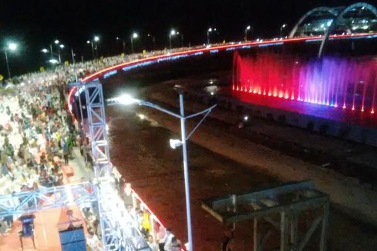 Cahaya warna-warni muncul bersamaan dengan air mancur di tengah Jembatan Suroboyo di Pantai Kenjerang, Surabaya, Sabtu (9/7/2016)/