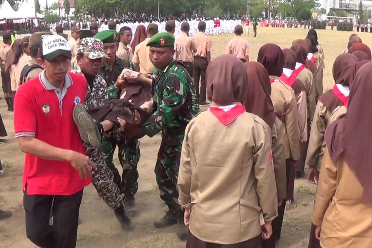 Sejumlah petugas tengah mengevakuasi seorang peserta upacara kemerdekaan di lapangam Syech Yusuf Sungguminasa, Kabupaten Gowa, Sulawesi Selatan lantaran terjatuh pingsan. Kamis, (17/8/2017).